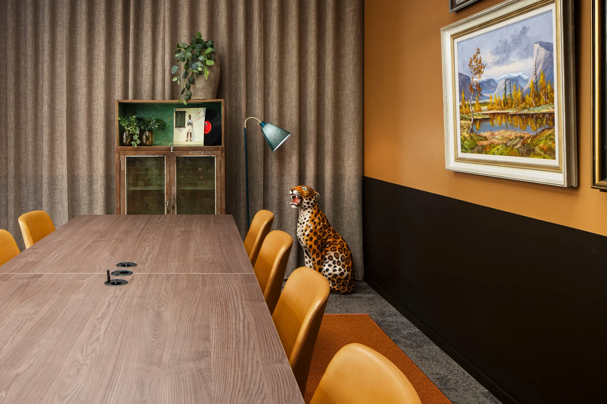 Kreativt og fargerikt møterom med konferansebord, gule stoler og en dekorativ leopardfigur